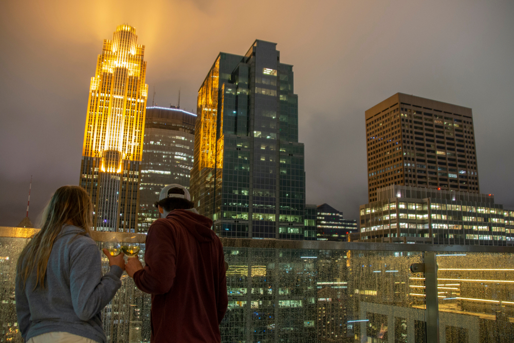 Young couple stands in front of the Minneapolis skyline at night