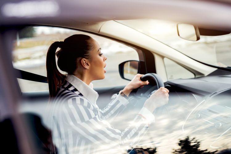 Young woman driver looking at her dashboard lights in concern