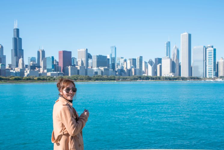 Young lady stands with Chicago skyline in the background and Lake Michigan