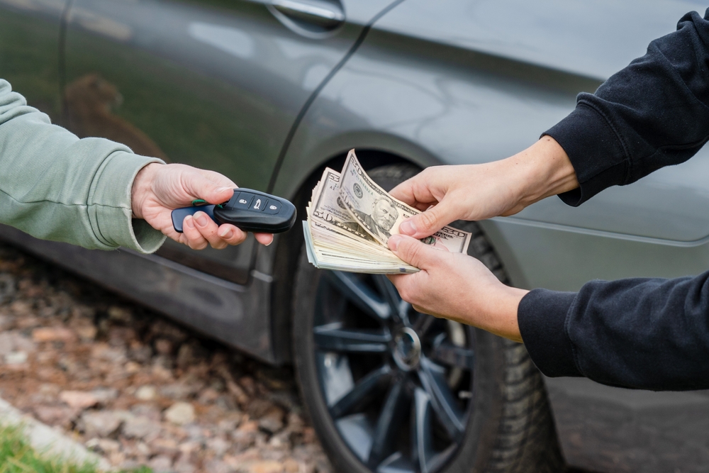 Hands hand over cash to buy a car and receive car keys