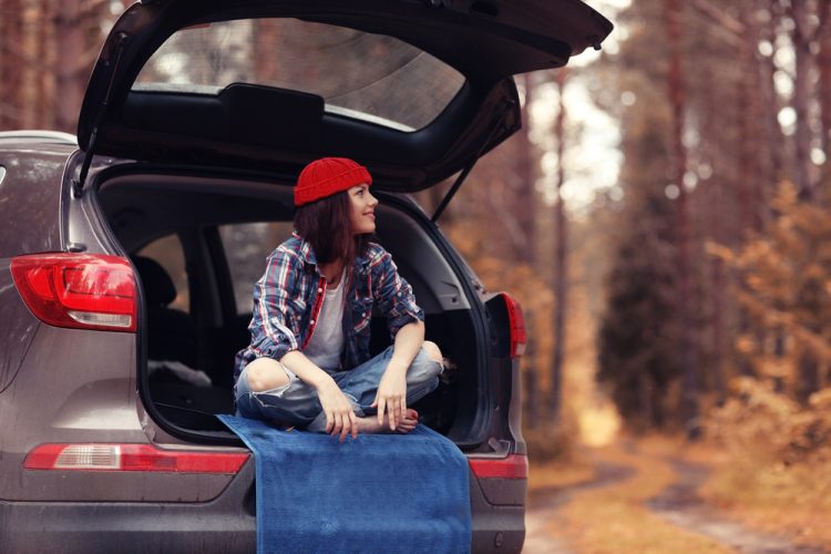 young woman sitting in the back of her SUV in the woods