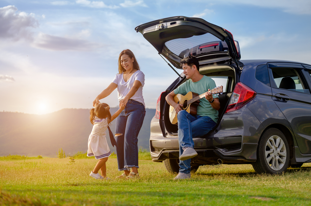 Young Asian family with their SUV on family trip