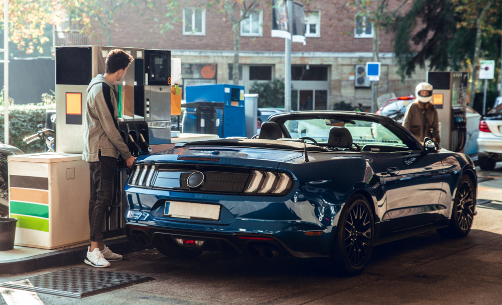 Young man fills up his sports car at the gas station