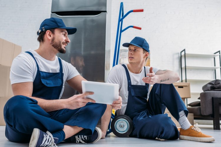 Professional movers take a break from moving a refrigerator