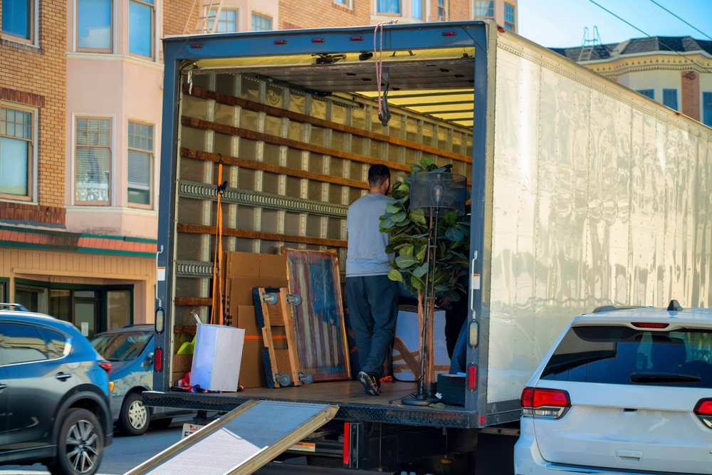 Man seen from behind loading things into a rental truck on moving day