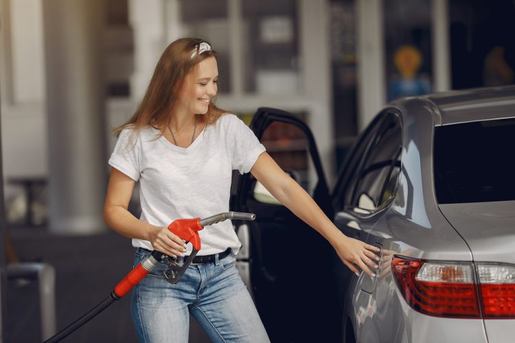 Young woman puts gasoline in her car