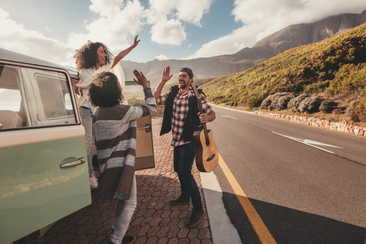 Several people outside a microbus on a roadtrip to see weird roadside attractions