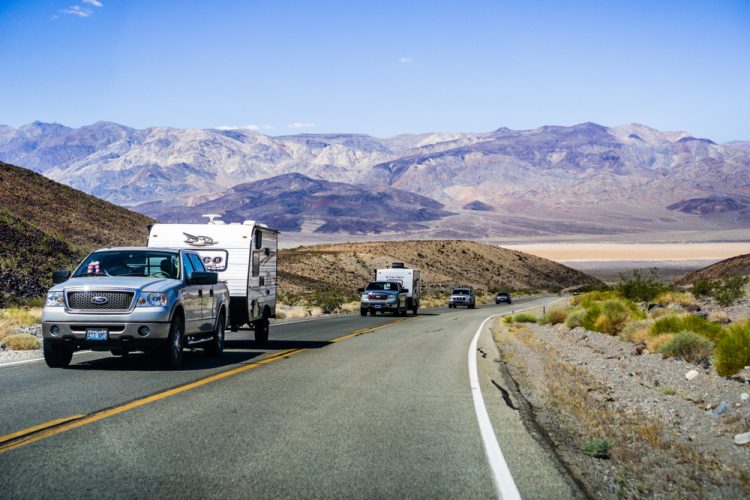 A caravan of trucks tow campers in a mountain area