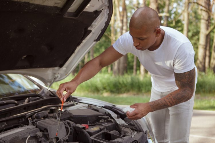 An African-American man checks his oil