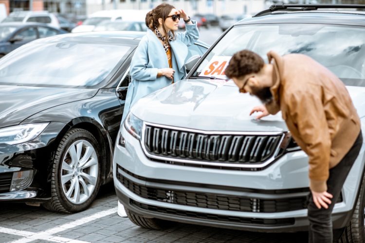 Young couple examines used cars at a car lot