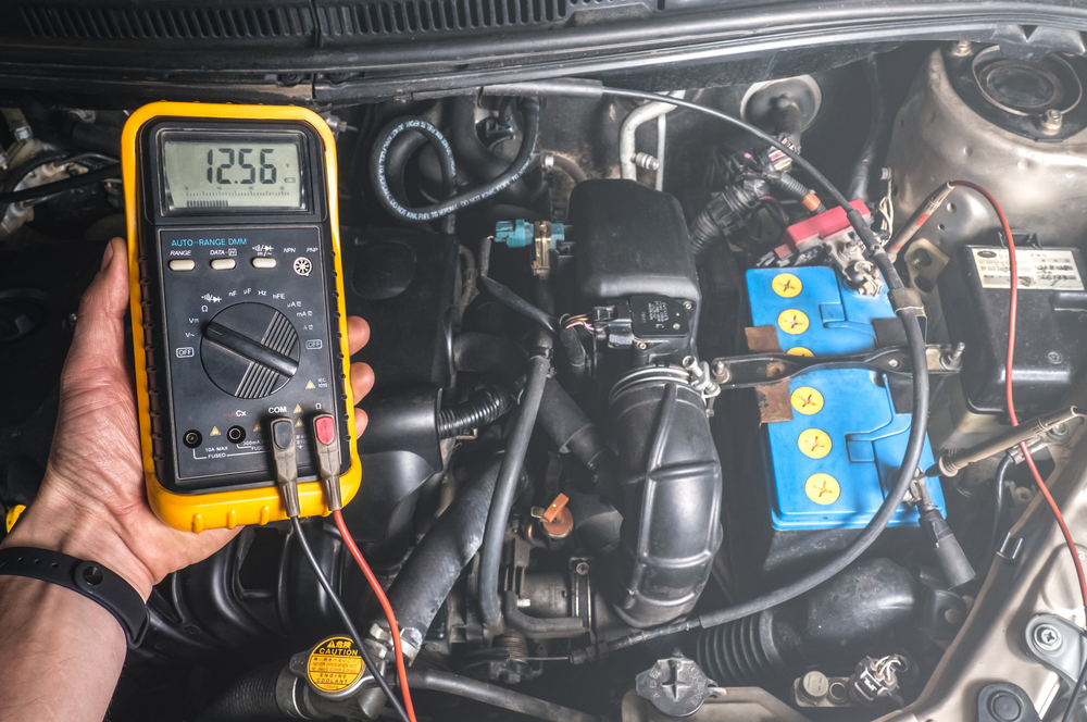 Hand holding a multimeter to check the battery