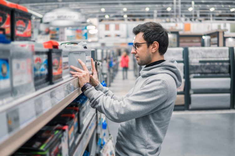 Man choosing a battery from a shelf in a store