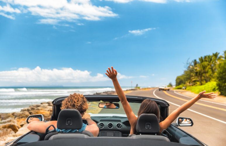 Friends driving in a convertible along the road by the ocean - car insurance in Florida