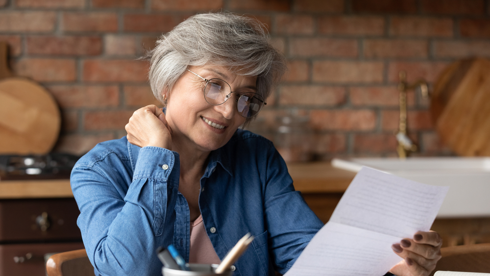 Senior woman is smiling as she examines medical bill from urgent care - health insurance