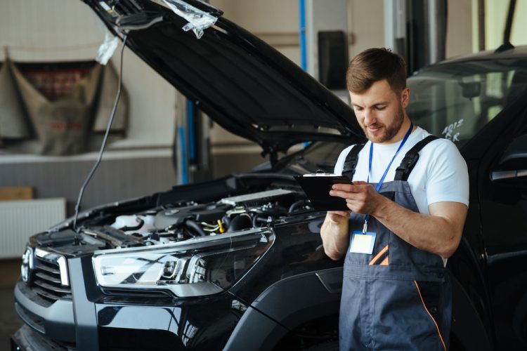 Mechanic checks off items on a car tune-up checklist - cheap car insurance