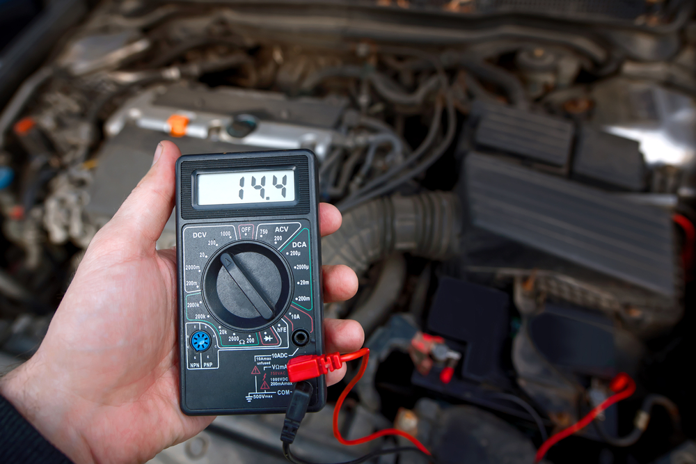 A hand holding a voltage meter checking the alternator charge - cheap car insurance.