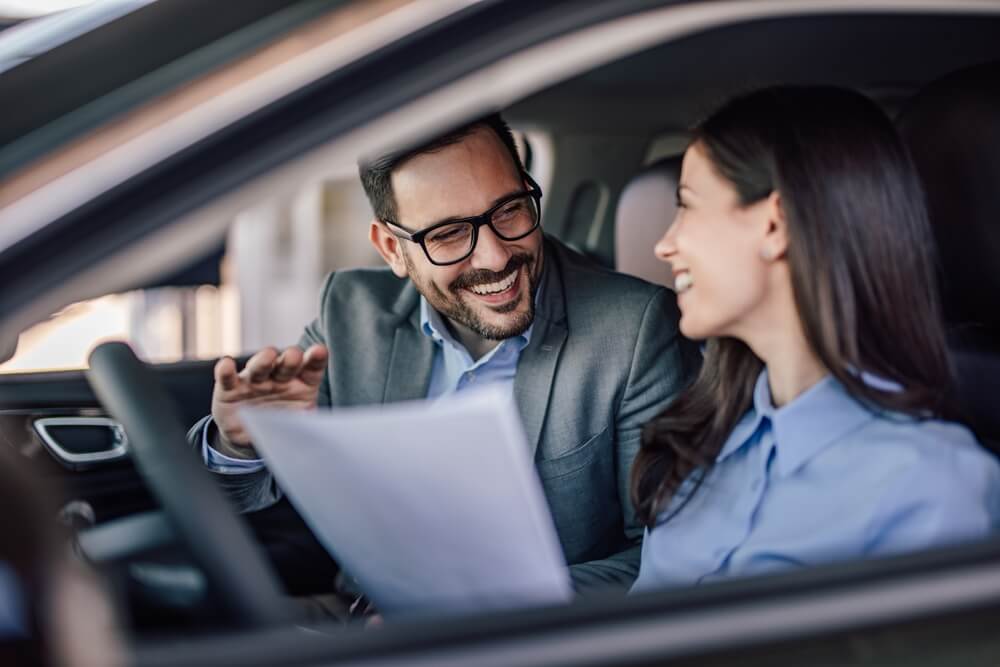 Driver reviewing paperwork with a dealership representative to understand requirements when you finance your car.