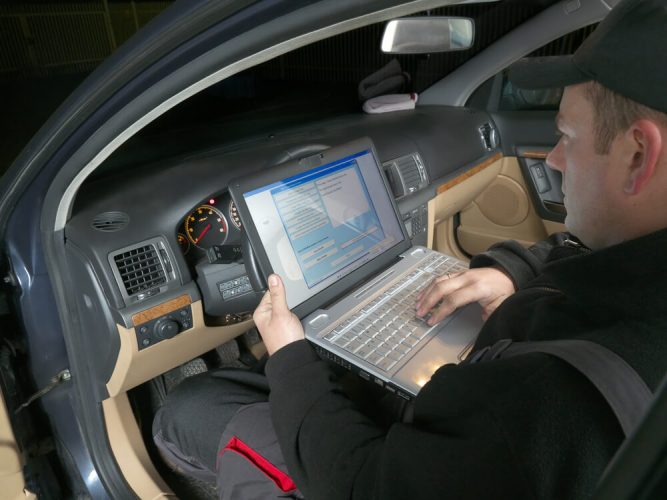 A vehicle inspection technician checks the car's VIN against records.