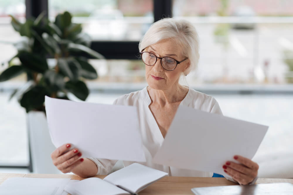 Senior woman compares two car insurance policies to see if she should switch.