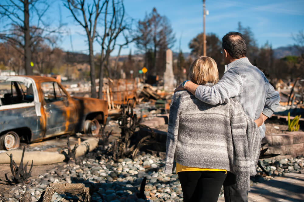 Couple standing looking at their burned home.