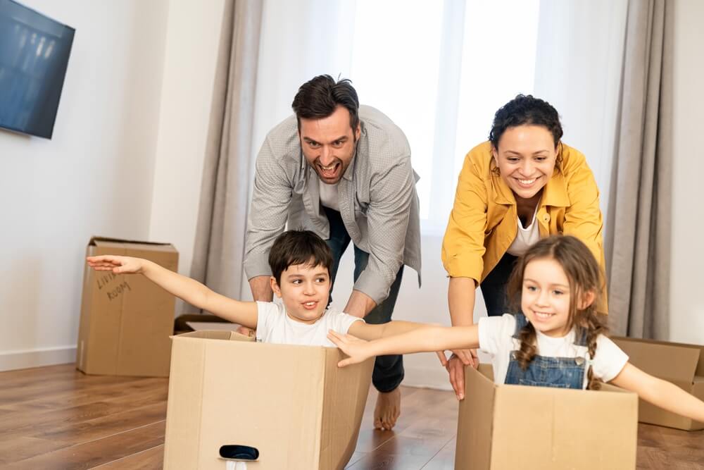 Parents push children through new home in moving boxes - cheap home and auto insurance.