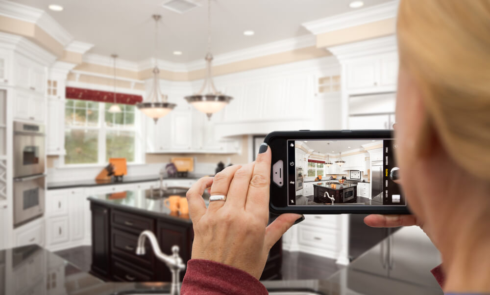 A woman takes pictures of her kitchen for a home inventory for renters insurance.