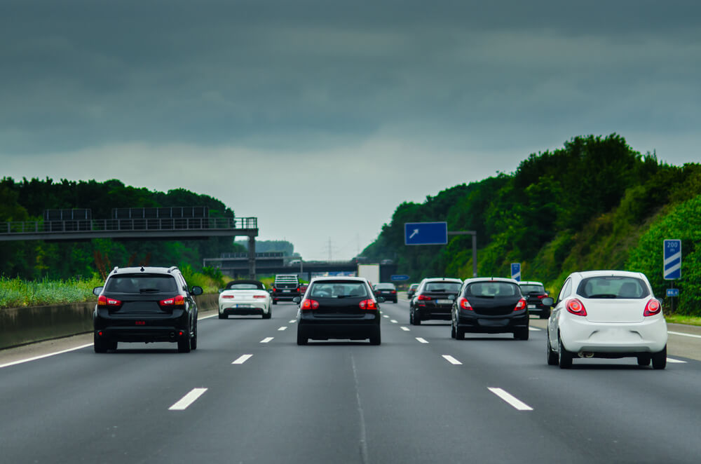 Black and white cars driving together on a highway - cheap car insurance.