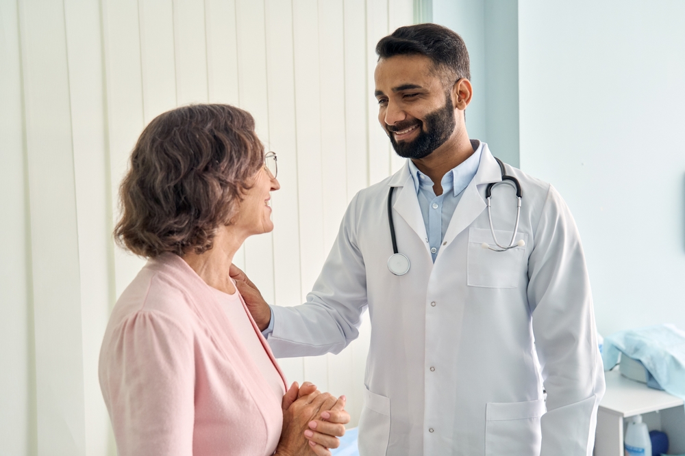 Older woman patient speaks with smiling doctor.