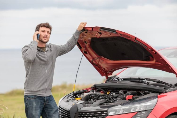 Man stands next to his car with the hood up - cheap roadside assistance and auto club.