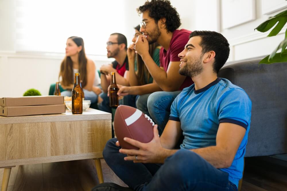 A group of friends gather to watch the football big game - cheap home insurance.
