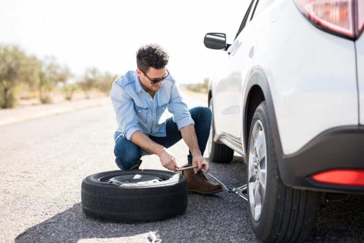 Man next to a flat tire - Freeway Insurance