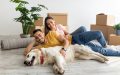 A couple lies on the floor in their rental apartment with their dog.