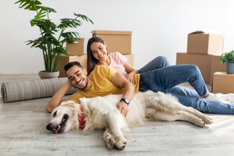 A couple lies on the floor in their rental apartment with their dog.