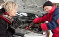A roadside assistance technician helps jump start a woman's stranded car - cheap roadside assistance.