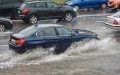 A car drives through a flooded street - cheap car insurance.