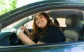 Attractive plus size woman laughing while driving her car looking cheerful and smiling - cheap rideshare insurance.