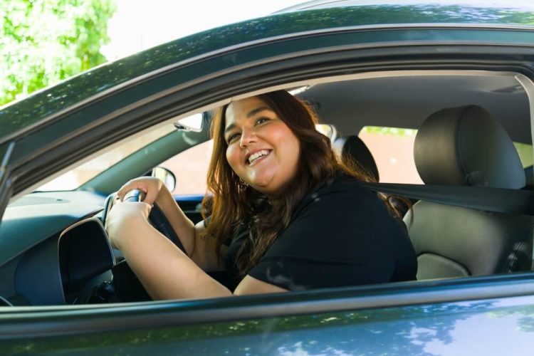 Attractive plus size woman laughing while driving her car looking cheerful and smiling - cheap rideshare insurance.