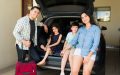 Man, woman and children loading up the car for a road trip.