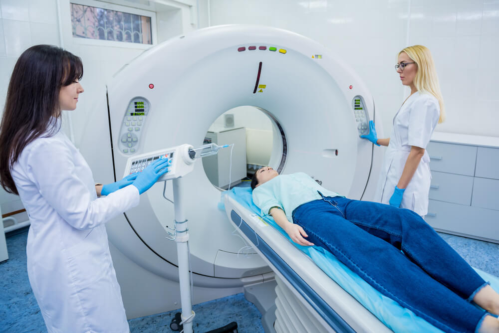 Medical professionals prepare a woman patient to receive a CT scan.