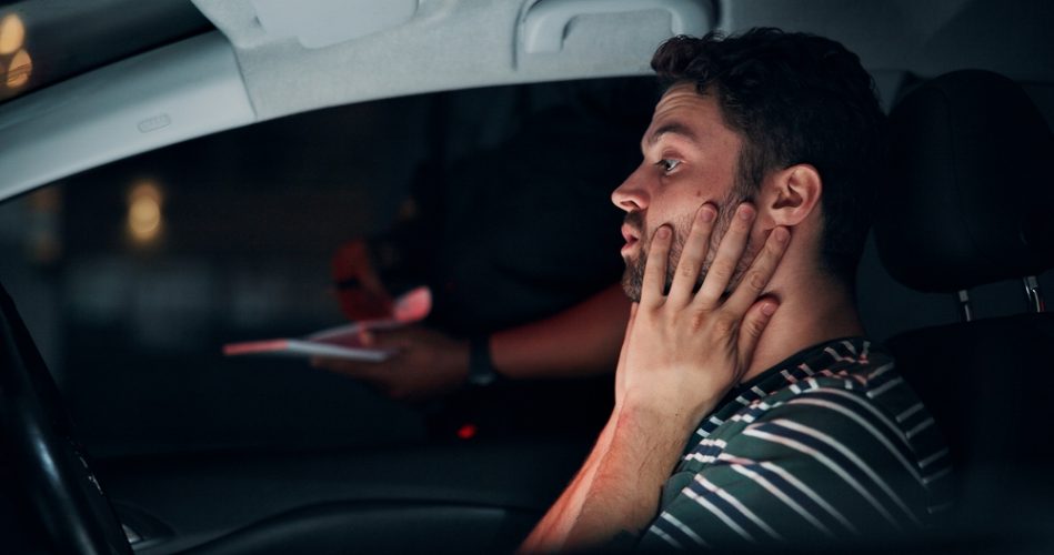 Young man driver gets pulled over by the police at night.