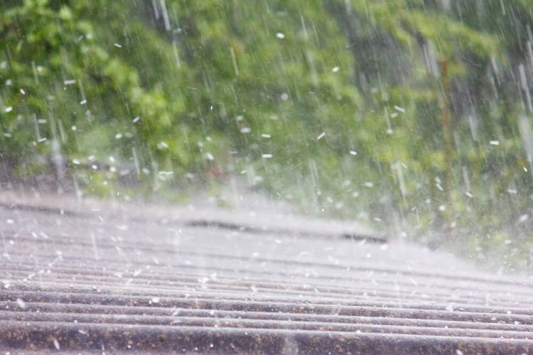 A roof is pounded by hail during a storm - cheap homeowners' insurance to protect against hail damage.