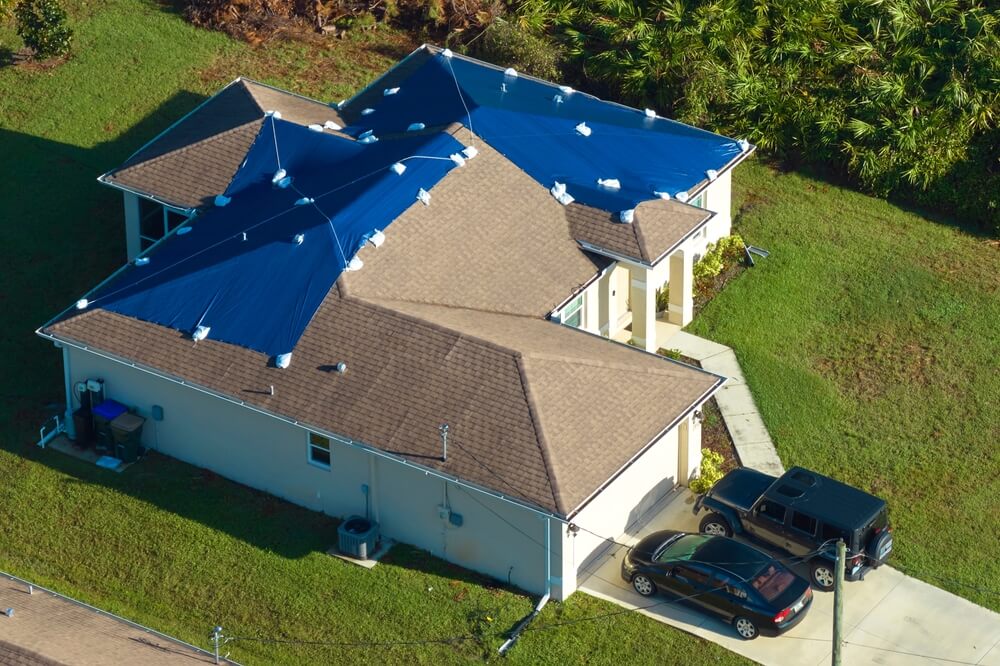 A roof has temporary covering after hailstorm damage - cheap homeowners insurance.