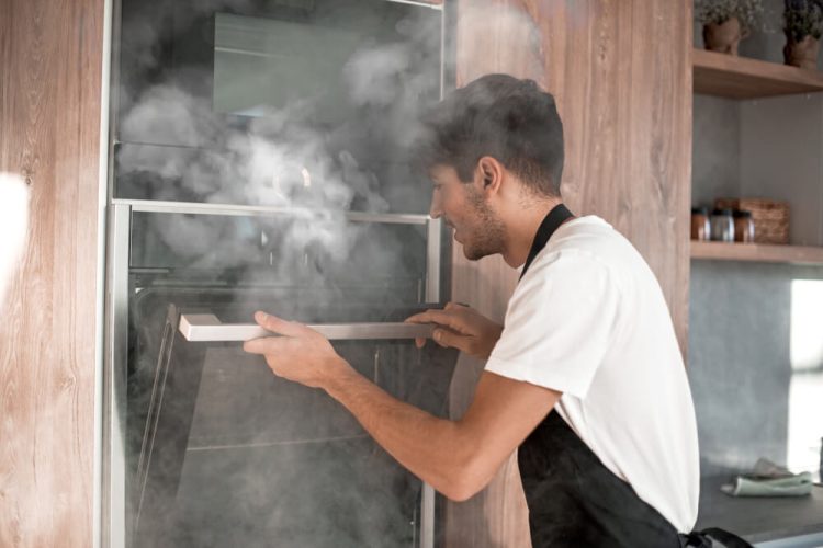 Man's oven is smoking, illustrating the need for a home warranty that protects appliances - cheap home insurance.