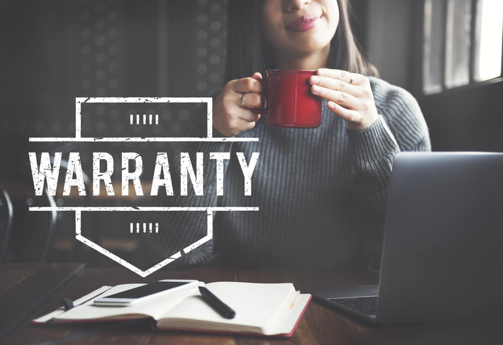 Woman smiles and drinks her cup of coffee with a badge for warranty on the screen - cheap home insurance.