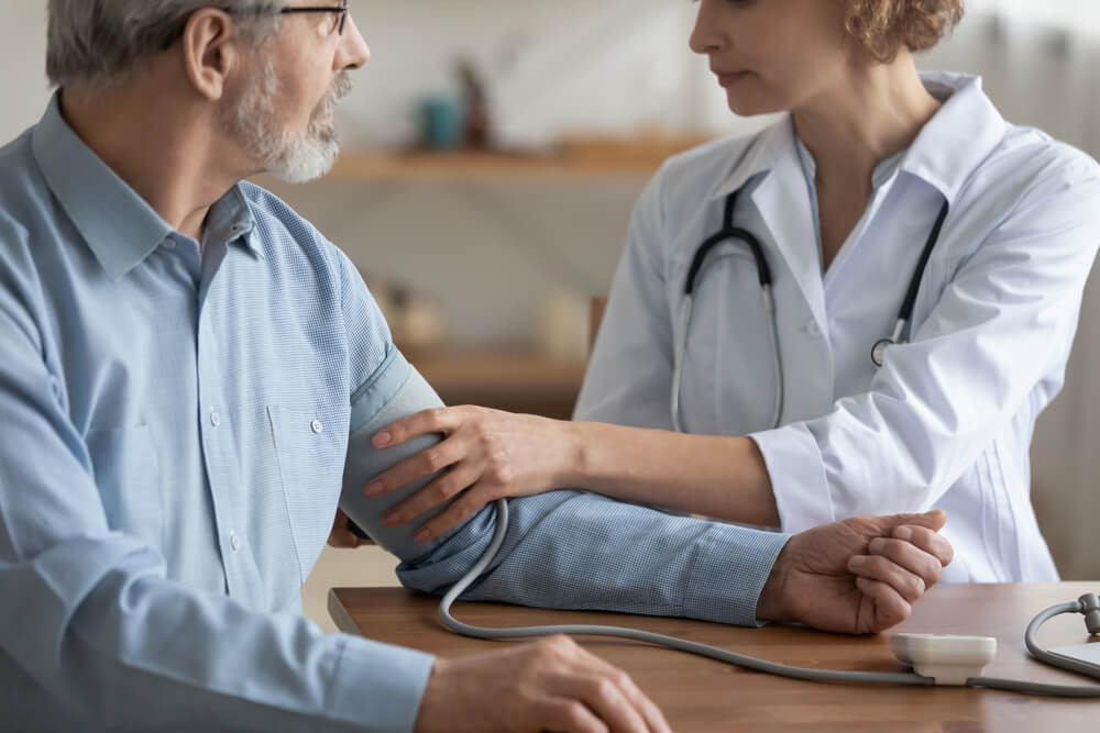 A female medical professional checks the blood pressure of an older man, illustrating the need for preventive care - cheap health insurance.