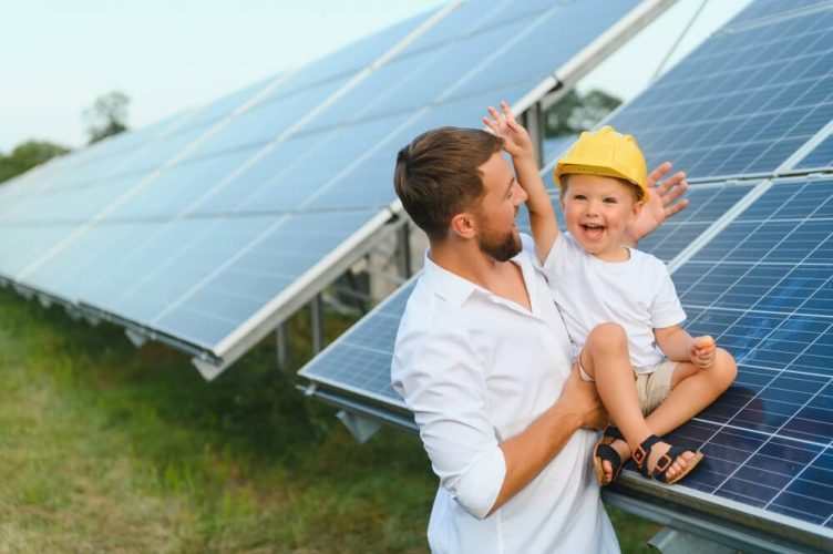 Man holds child next to solar panels, how does home insurance work with solar panels.