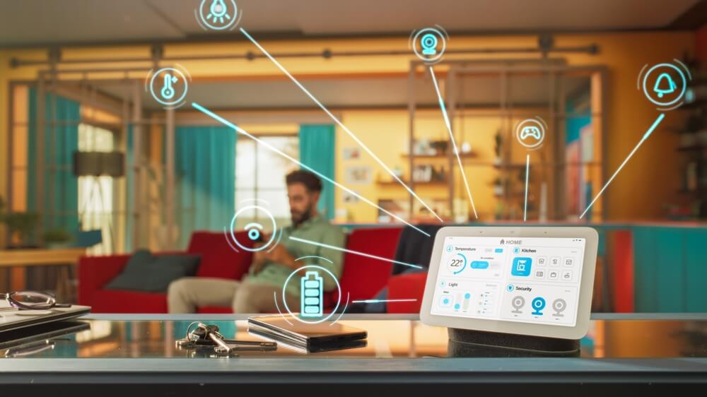 Man sits on couch in background, device in foreground monitors household functions, set temperatures, concept of home insurance with smart home