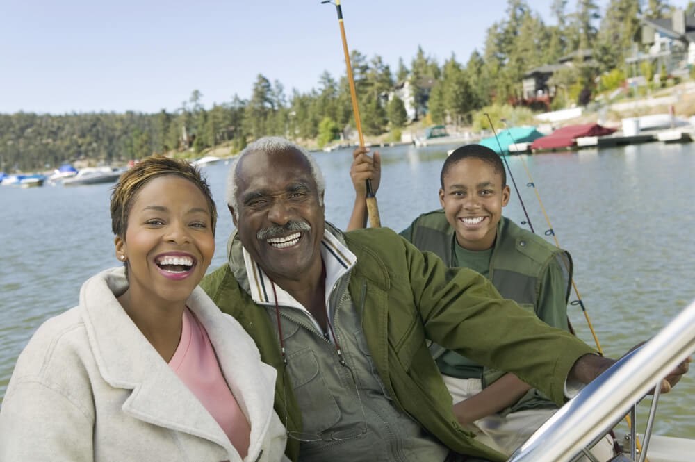 Portrait of a senior man with daughter and grandson fishing together, on his boat with boat insurance near me to find the best local options.