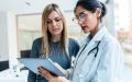 Shot of female doctor talking while explaining medical treatment with digital tablet to patient in the consultation, maximizing your Covered California health insurance.