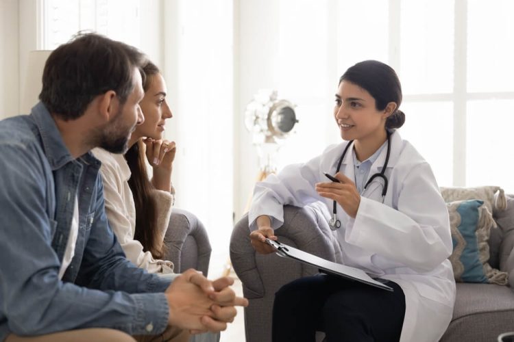 A medical professional talks to a young couple about switching their Covered California plan to find the right coverage.